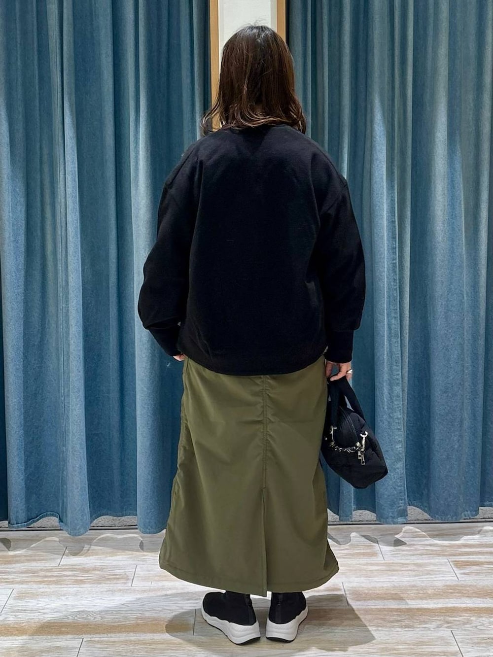 グリーン系のスカート、グレー系のTシャツ/カットソー、ブラック系のブルゾンを着用したレディースの冬コーディネートの3枚目の写真