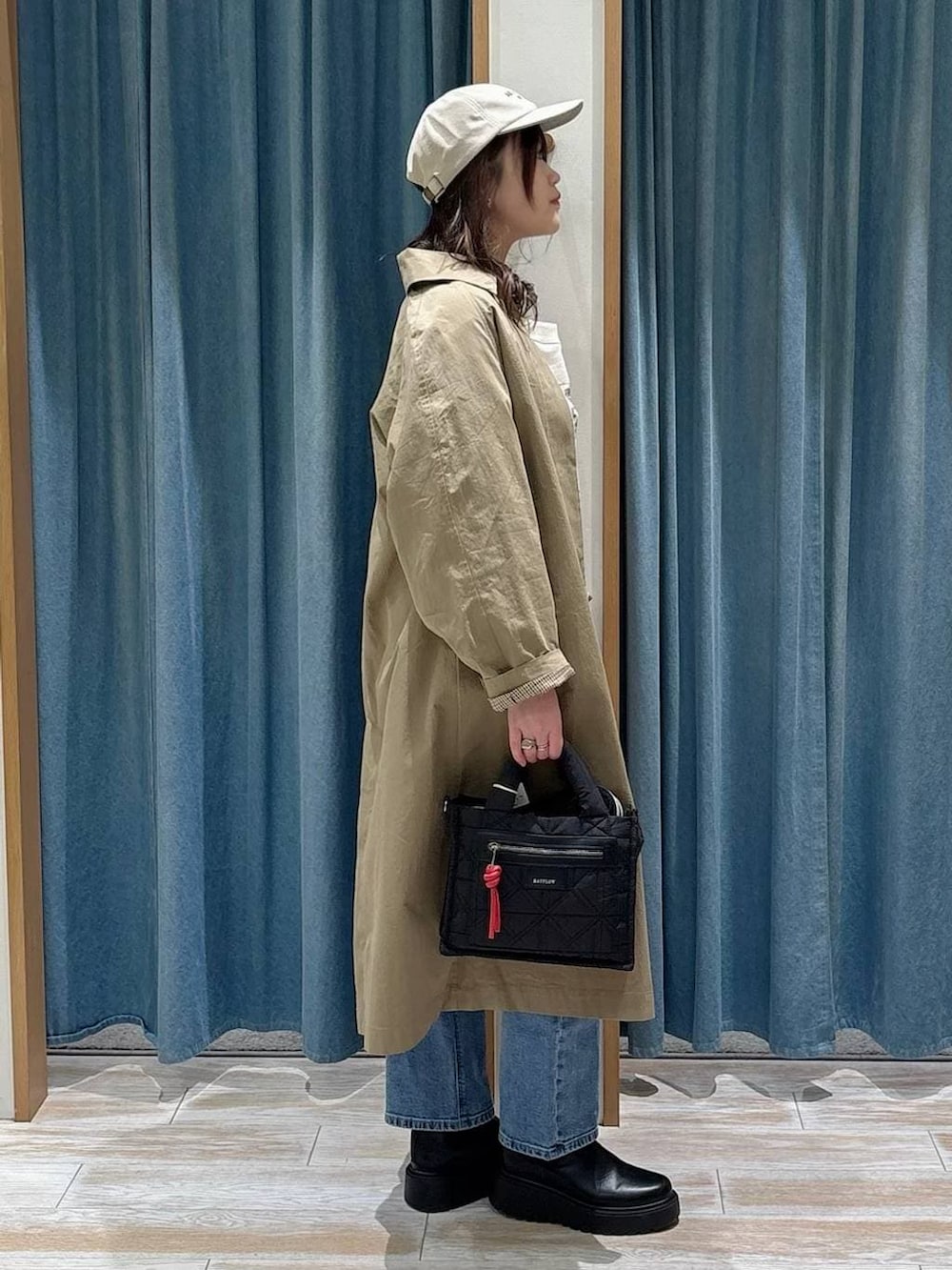 ブラック系のショルダーバッグ、ブラック系のブーツ、ブルー系のデニムパンツを着用したレディースの冬コーディネートの2枚目の写真