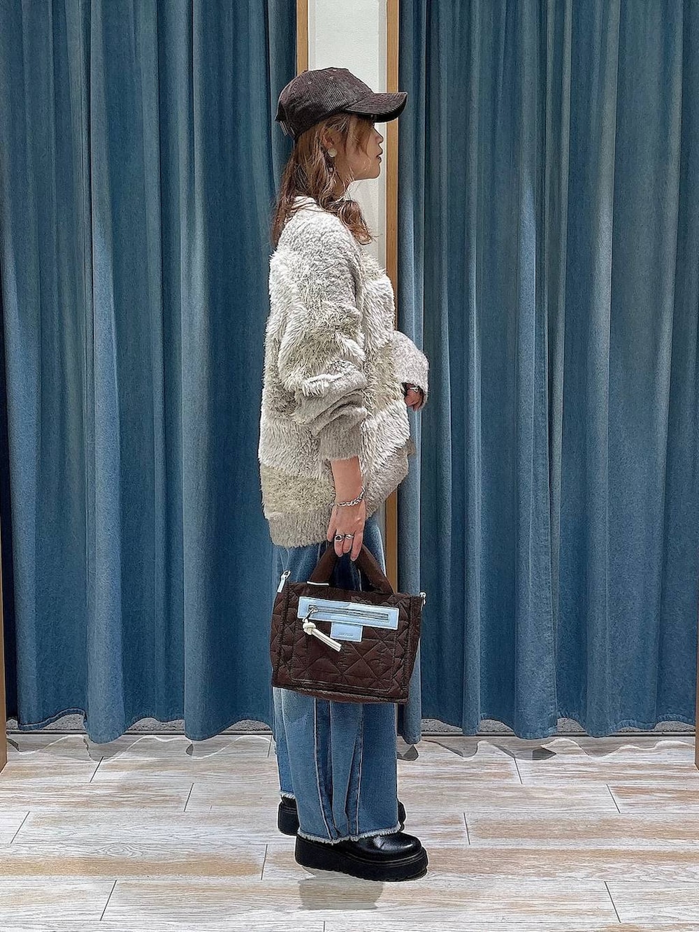ベージュ系のカーディガン/ボレロ、ブルー系のデニムパンツ、ブラウン系のショルダーバッグを着用したレディースの秋コーディネートの3枚目の写真
