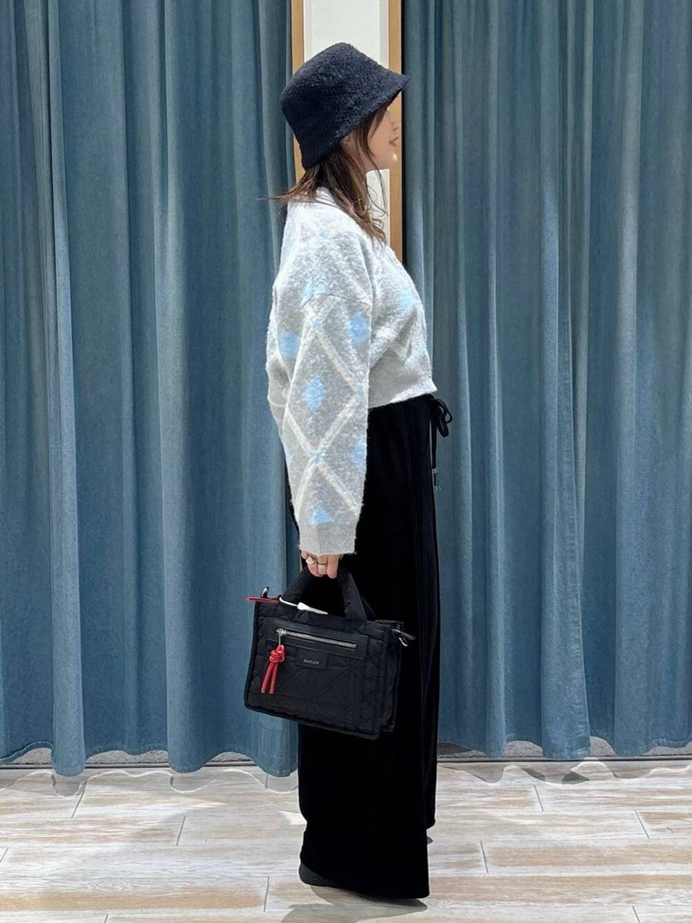 ブラック系のショルダーバッグ、グレー系のカーディガン/ボレロ、ブラック系のブーツを着用したレディースの秋コーディネートの2枚目の写真