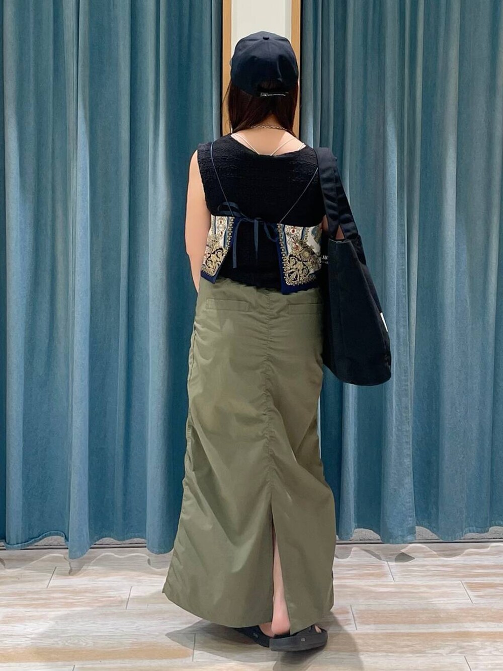 ブルー系のキャミソール、グリーン系のスカート、ブラック系のサンダルを着用したレディースの春コーディネートの3枚目の写真