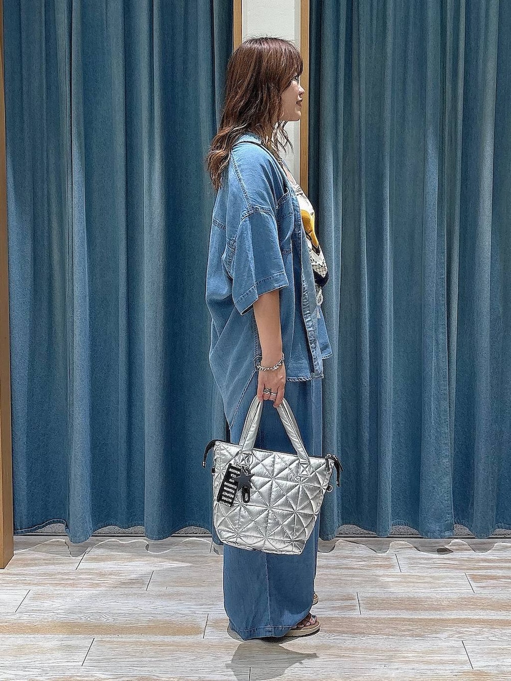 ブルー系のシャツ/ブラウス、シルバー系のトートバッグ、ブルー系のデニムパンツを着用したレディースの夏コーディネートの2枚目の写真
