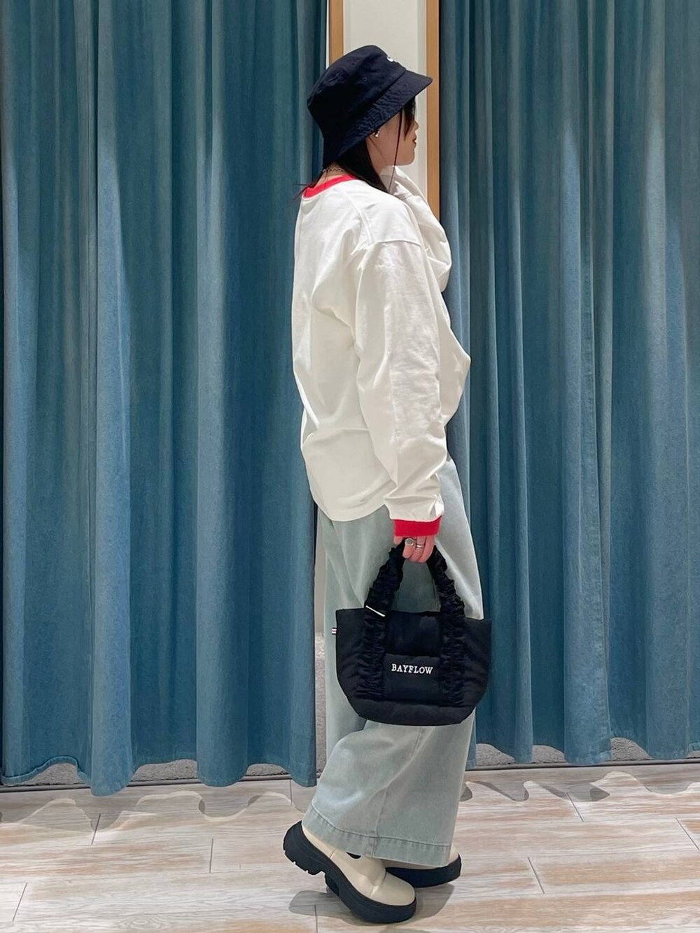 ホワイト系のブーツ、ブラック系のトートバッグ、グリーン系のデニムパンツを着用したレディースの冬コーディネートの2枚目の写真