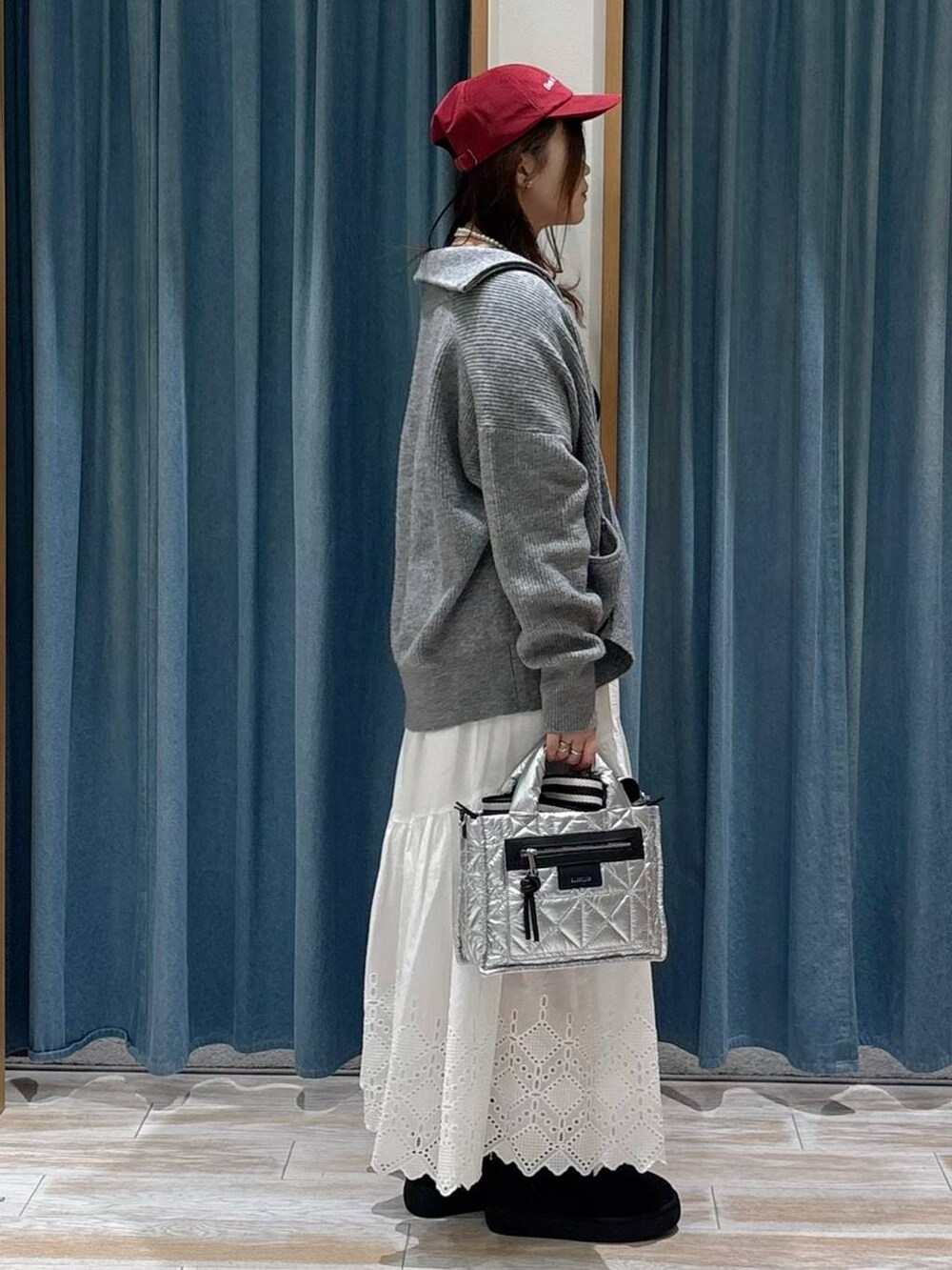 シルバー系のショルダーバッグ、ブラック系のブーツ、ブラック系のニット/セーターを着用したレディースの秋コーディネートの2枚目の写真