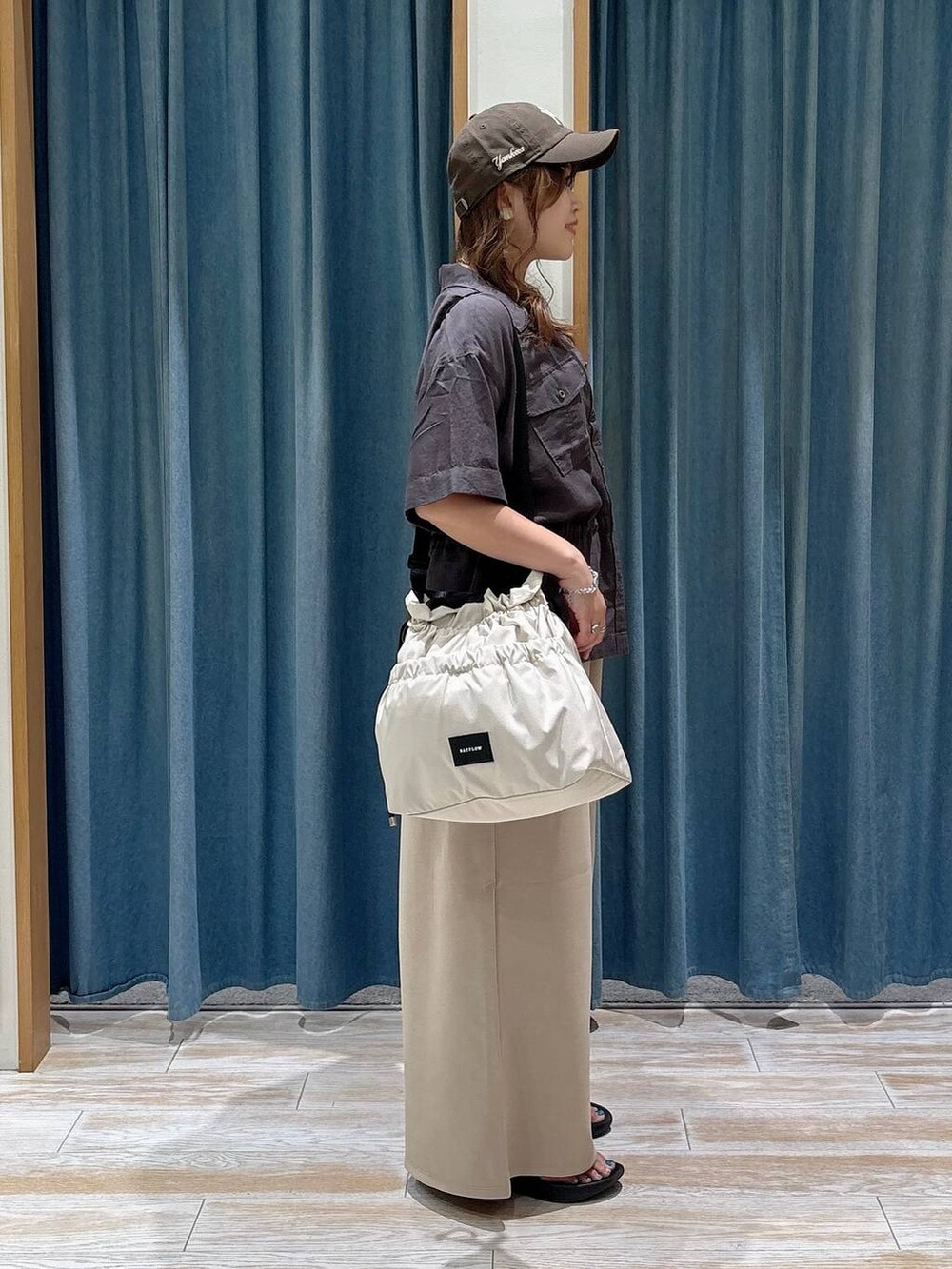 ホワイト系のトートバッグ、グレー系のシャツ/ブラウス、ブラック系のサンダルを着用したレディースの夏コーディネートの2枚目の写真