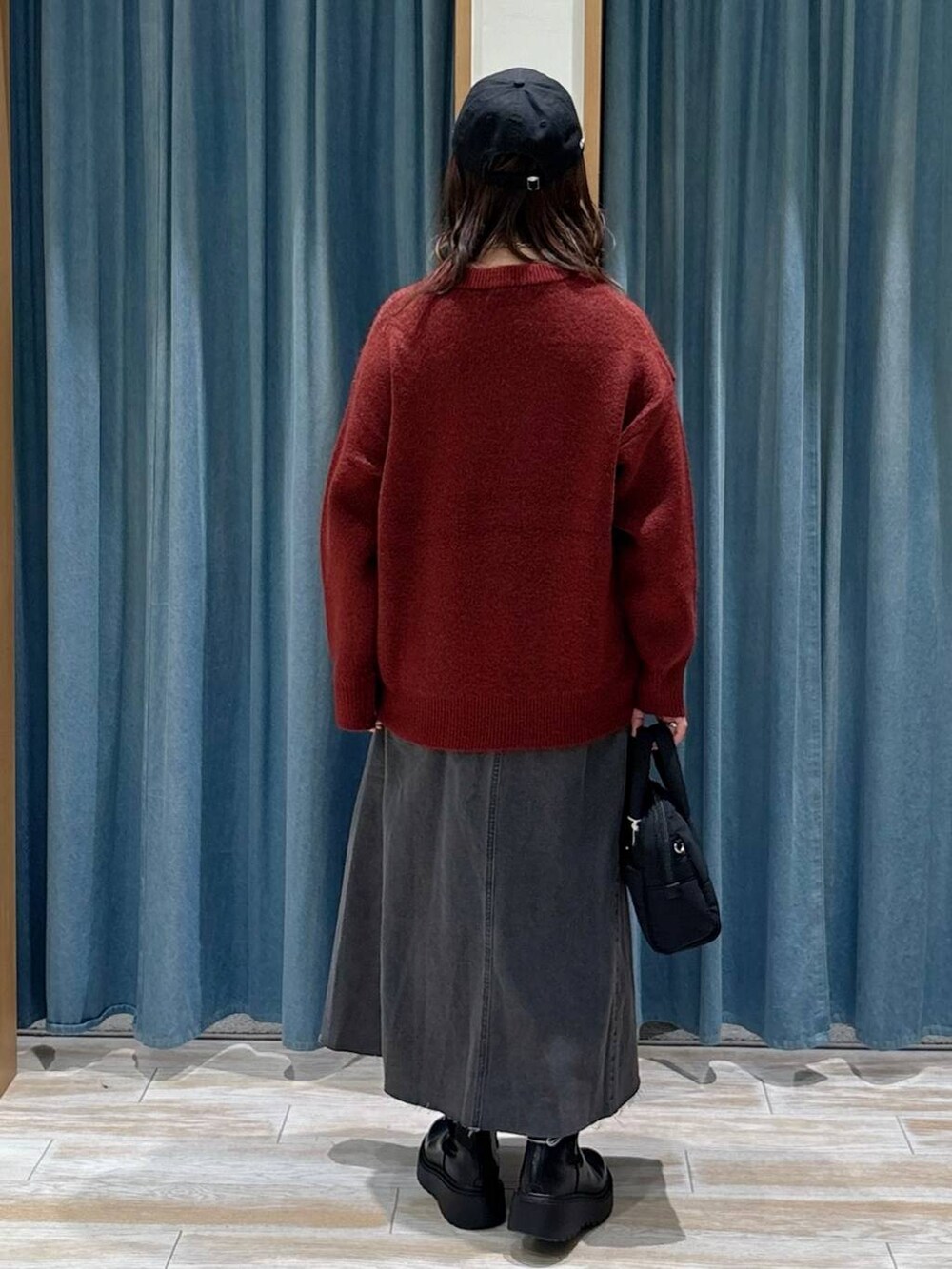 ブラック系のブーツ、ブラック系のスカート、ブラック系のボストンバッグを着用したレディースの秋コーディネートの3枚目の写真