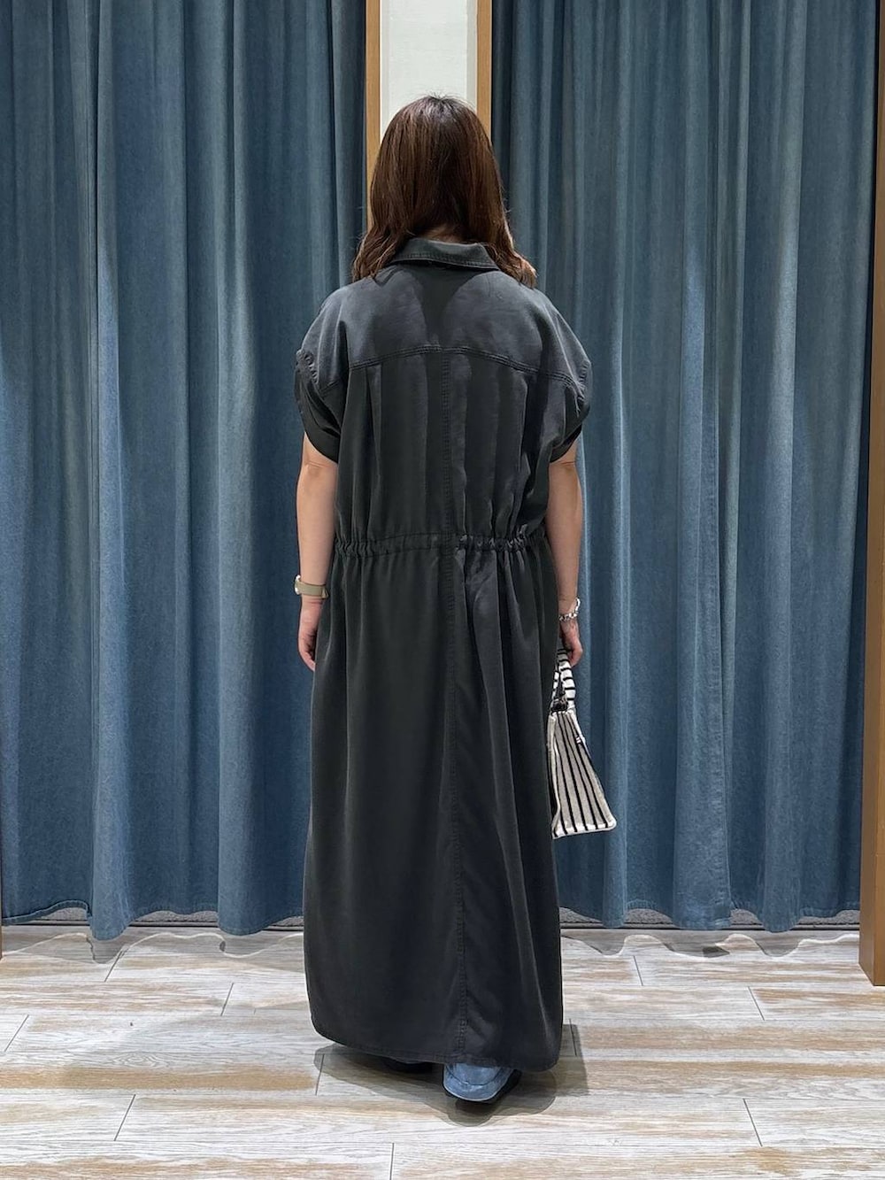 ブルー系のデニムパンツ、ブラック系のサンダル、ベージュ系のトートバッグを着用したレディースの夏コーディネートの3枚目の写真
