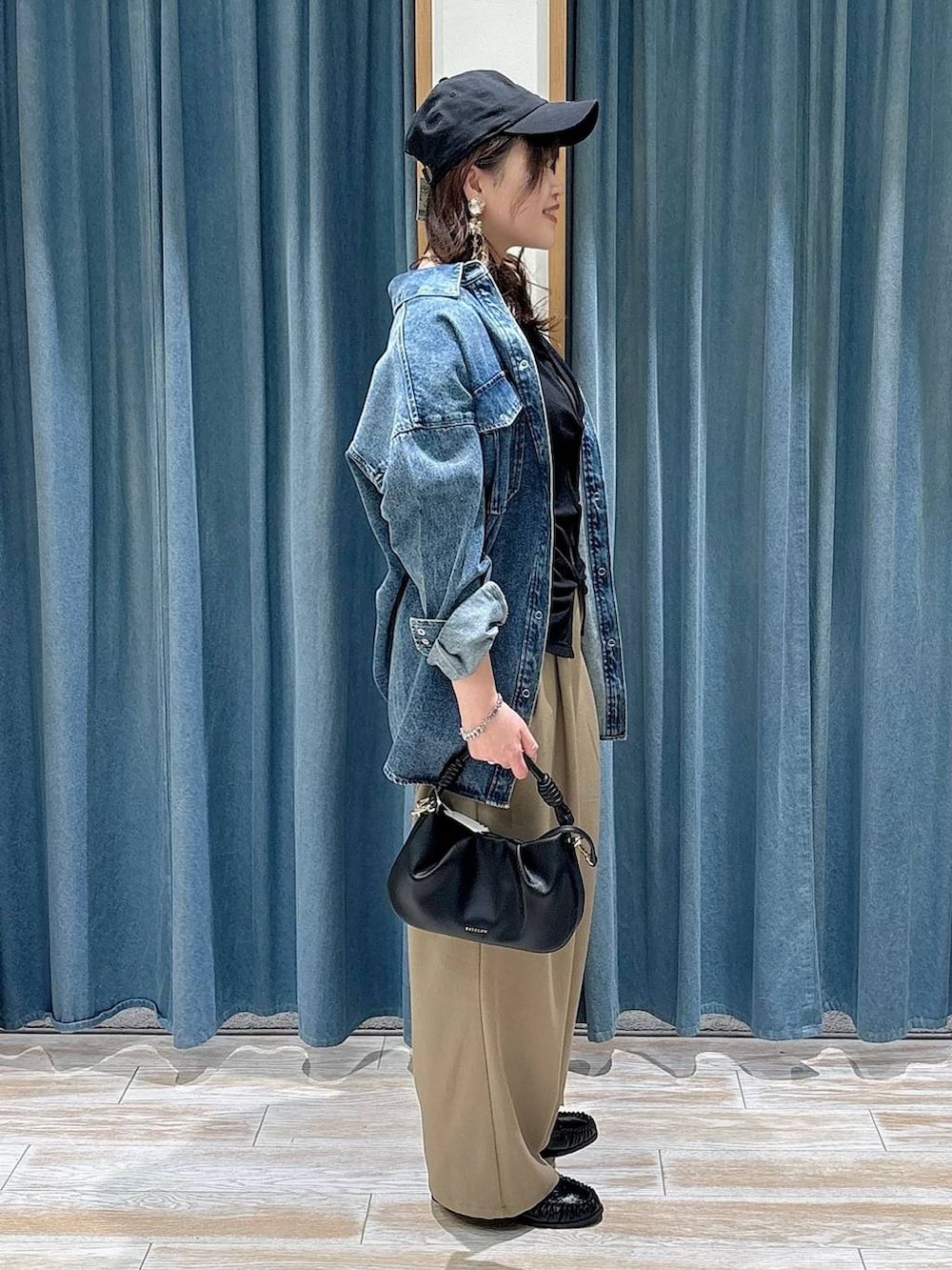 ブラック系のハンドバッグ、ブラック系のローファー、ブルー系のシャツ/ブラウスを着用したレディースの春コーディネートの2枚目の写真