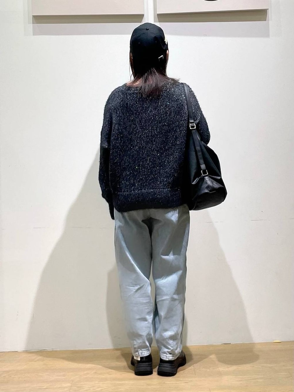 ブラック系のブーツ、ブラック系のニット/セーター、ブルー系のデニムパンツを着用したレディースの秋コーディネートの3枚目の写真