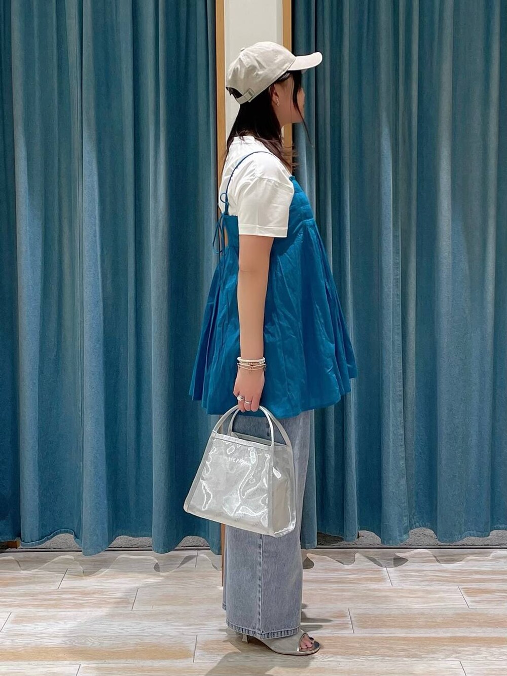 ブルー系のデニムパンツ、ホワイト系のTシャツ/カットソー、シルバー系のサンダルを着用したレディースの春コーディネートの2枚目の写真