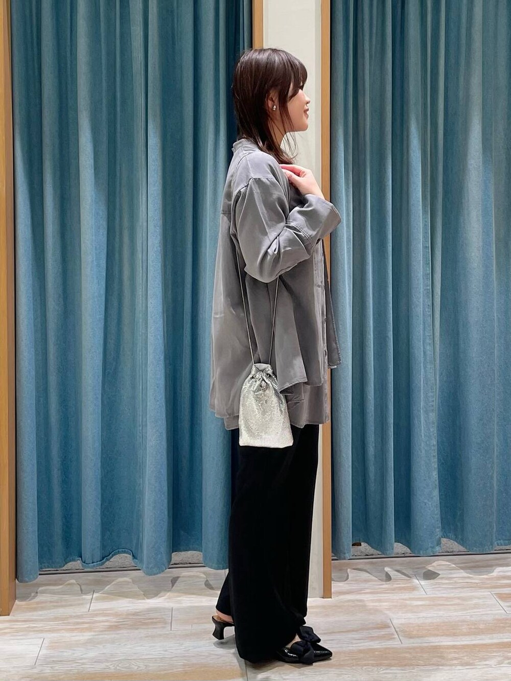 シルバー系のショルダーバッグ、グレー系のチュニック、ブラック系のパンプスを着用したレディースの冬コーディネートの2枚目の写真