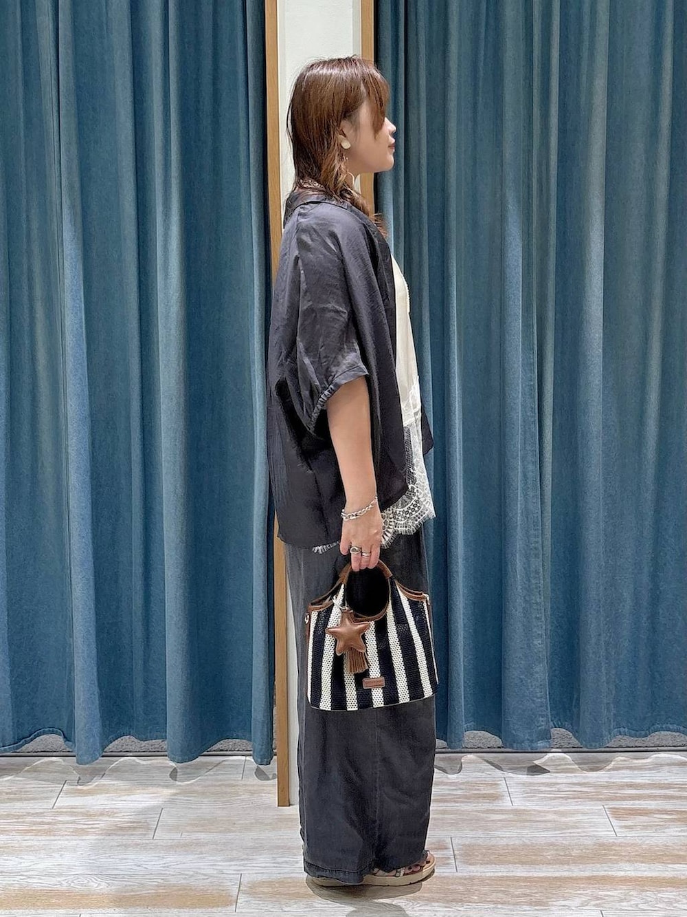 ブラック系のデニムパンツ、ブルー系のショルダーバッグ、シルバー系のサンダルを着用したレディースの夏コーディネートの2枚目の写真