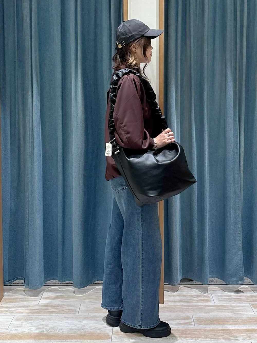 ブラック系のブーツ、ブルー系のデニムパンツ、ブラック系のショルダーバッグを着用したレディースの秋コーディネートの2枚目の写真
