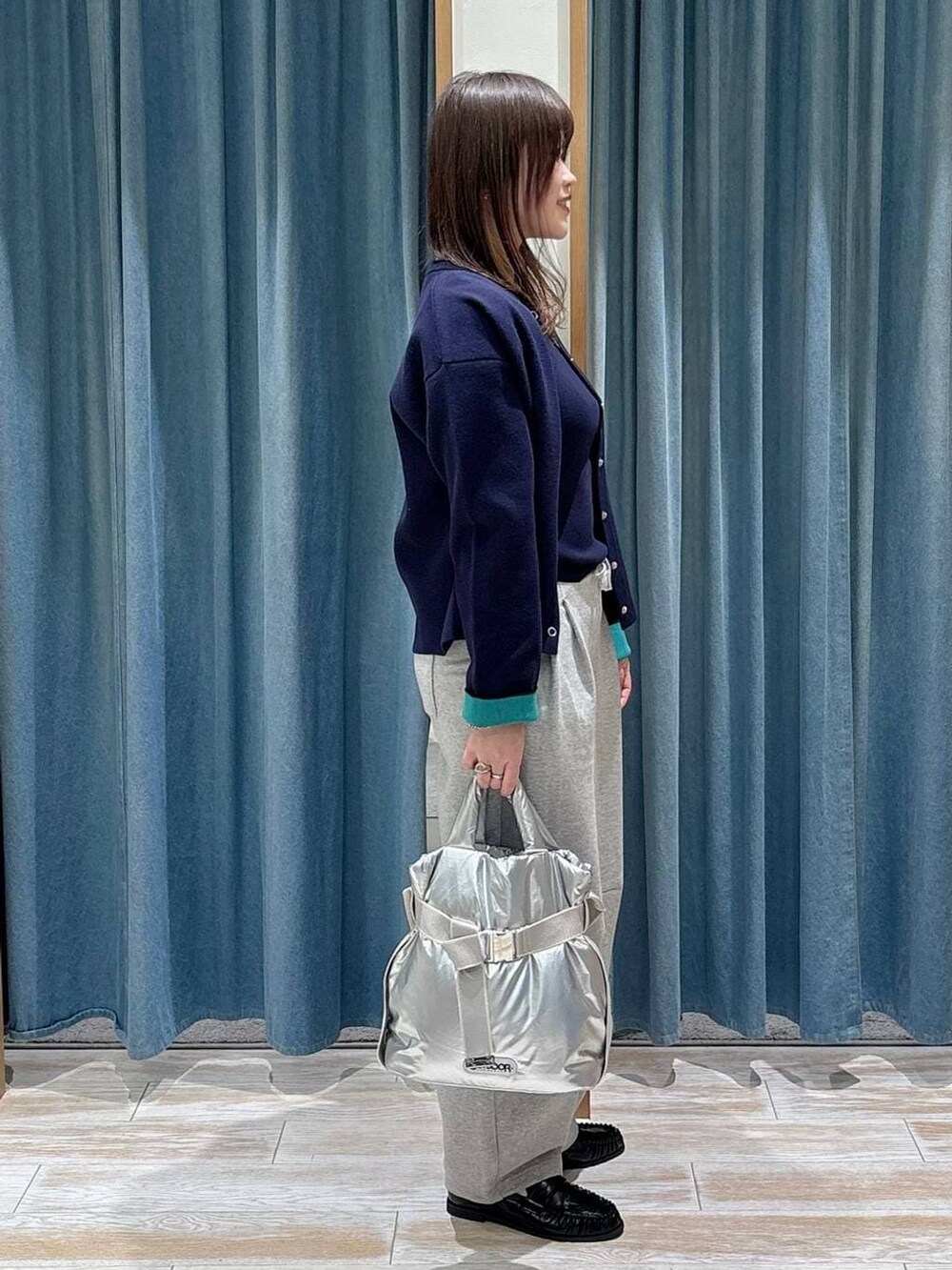 シルバー系のトートバッグ、ブラック系のローファー、ブルー系のカーディガン/ボレロを着用したレディースの冬コーディネートの2枚目の写真