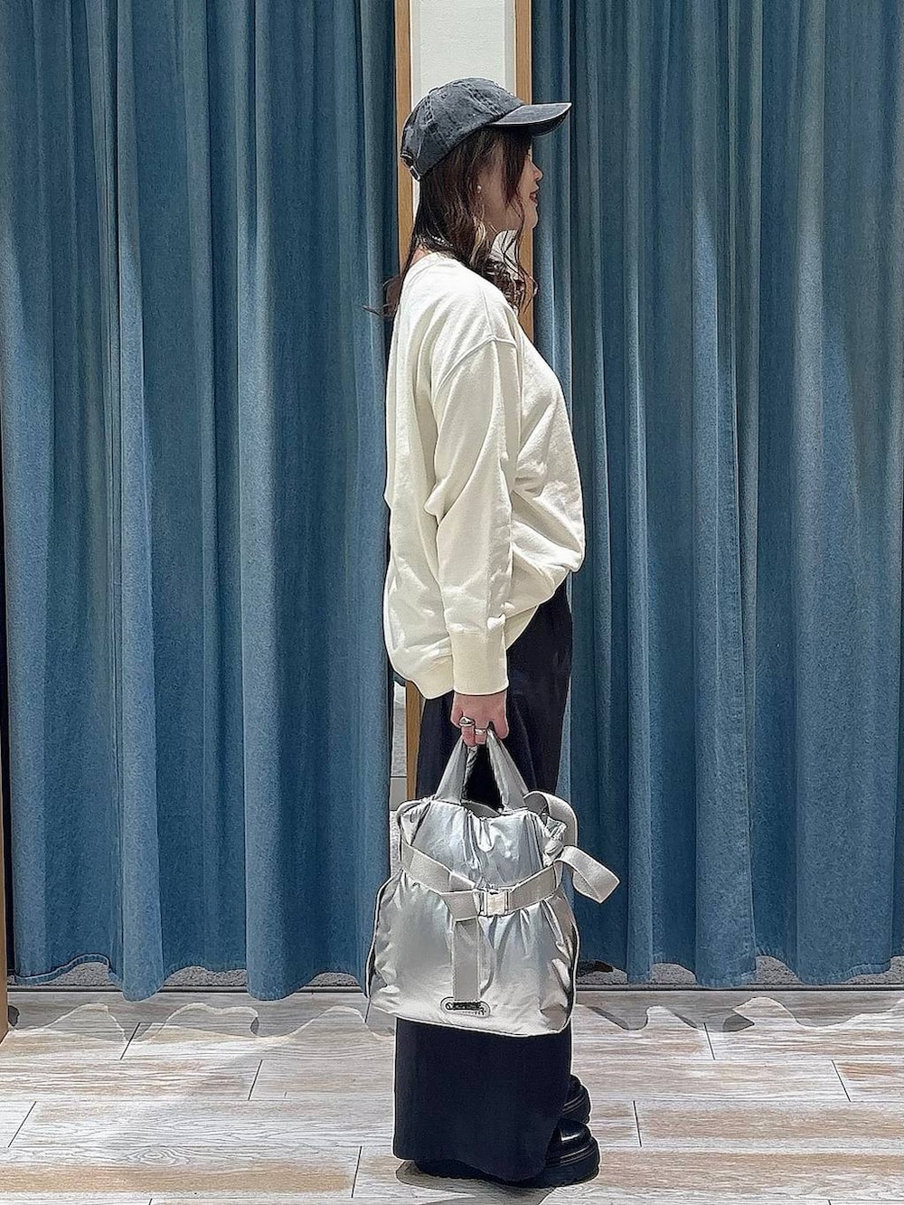 シルバー系のトートバッグ、ブラック系のブーツ、グレー系のその他パンツを着用したレディースの冬コーディネートの2枚目の写真