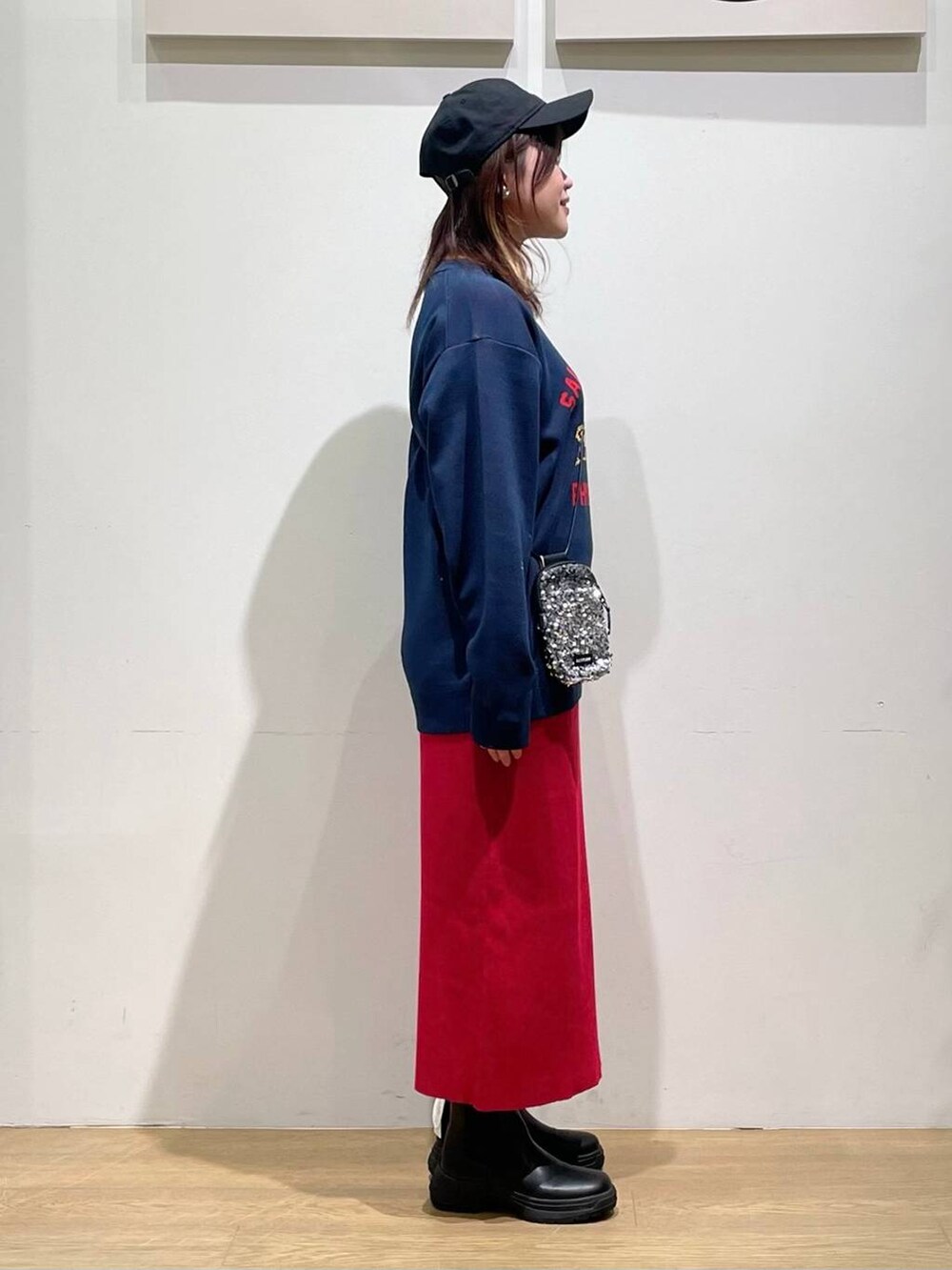 グレー系のショルダーバッグ、ブルー系のニット/セーター、レッド系のスカートを着用したレディースの秋コーディネートの2枚目の写真