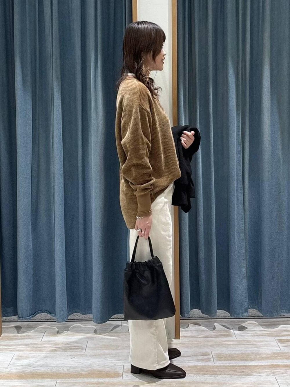 ブラック系のブルゾン、ブラウン系のブーツ、ブラック系のハンドバッグを着用したレディースの秋コーディネートの2枚目の写真