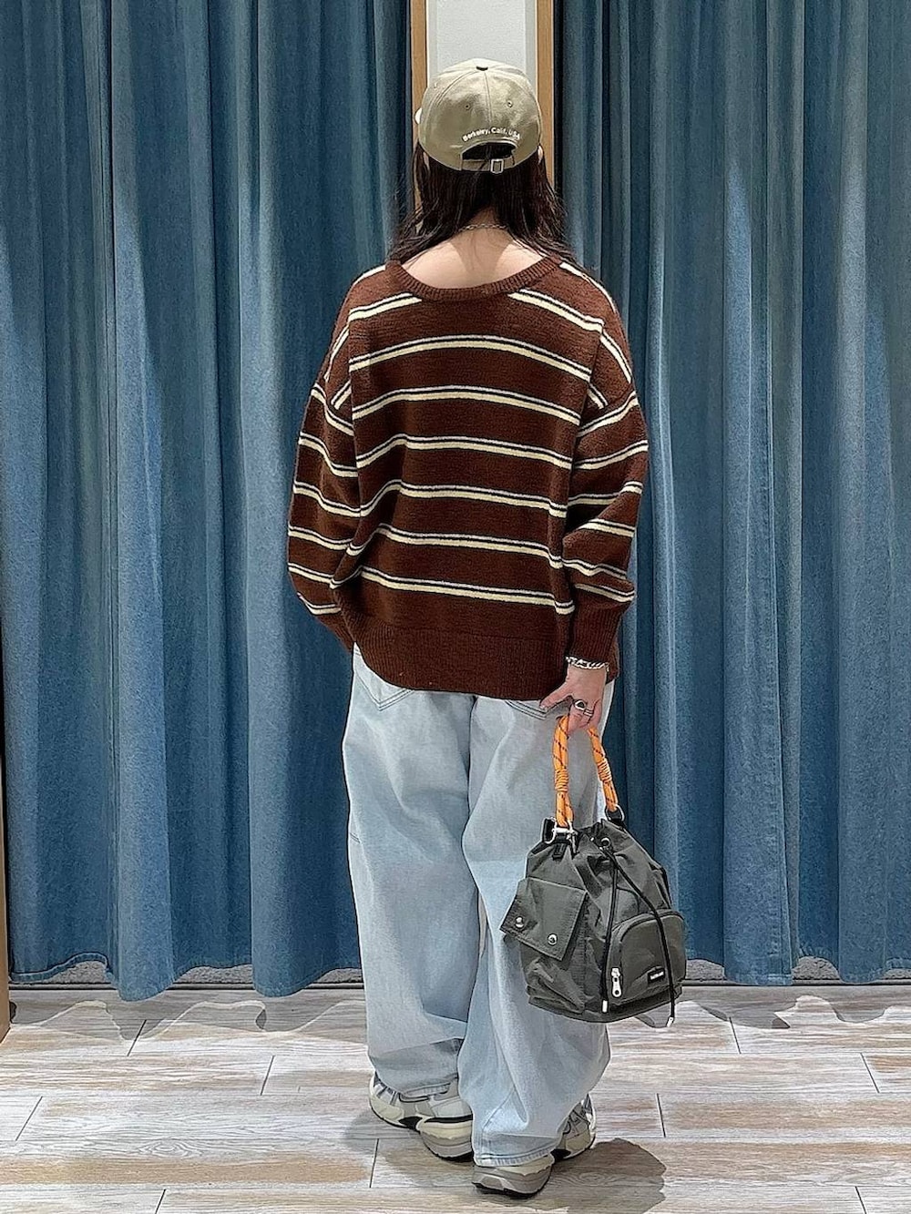 グリーン系のハンドバッグ、ブルー系のデニムパンツ、ブラウン系のニット/セーターを着用したレディースの冬コーディネートの3枚目の写真