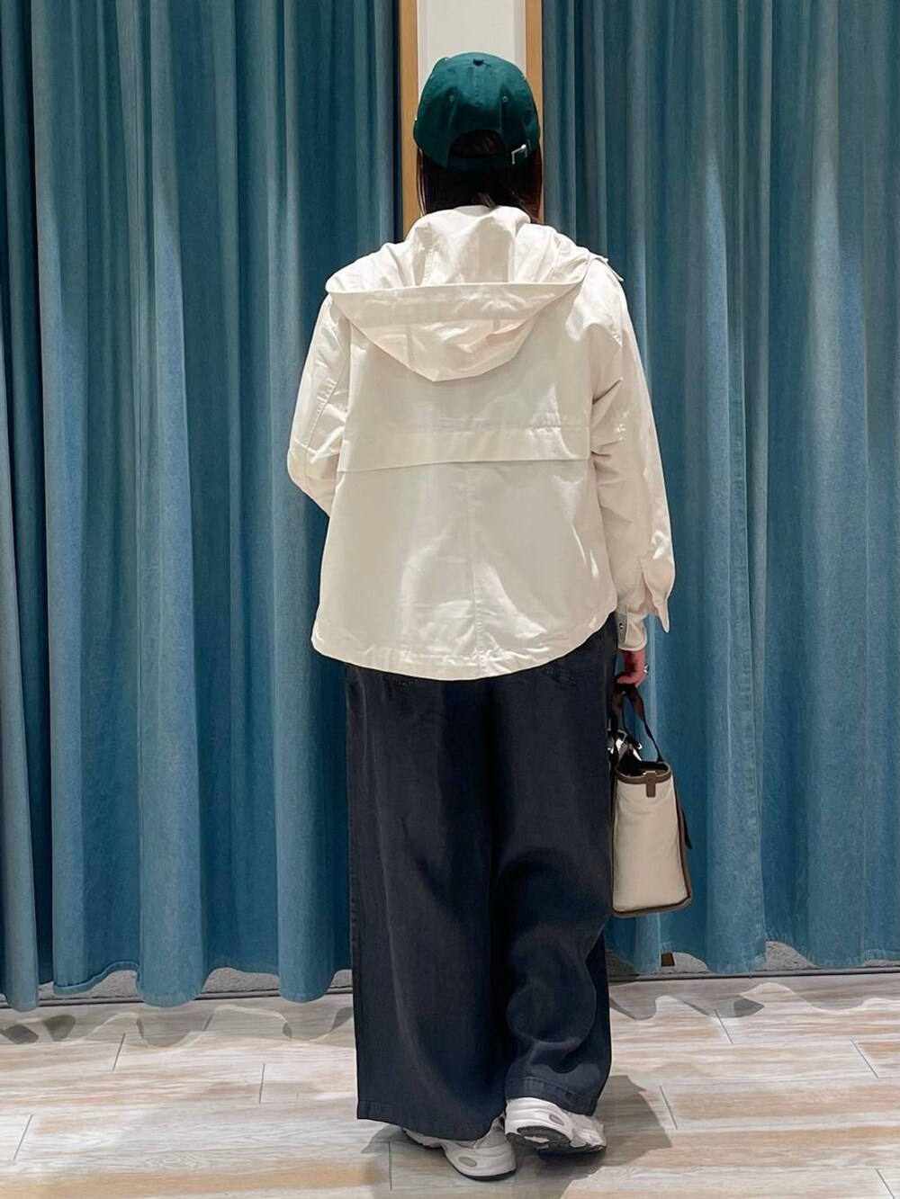 ホワイト系のマウンテンパーカー、ベージュ系のトートバッグ、ホワイト系のTシャツ/カットソーを着用したレディースの春コーディネートの3枚目の写真