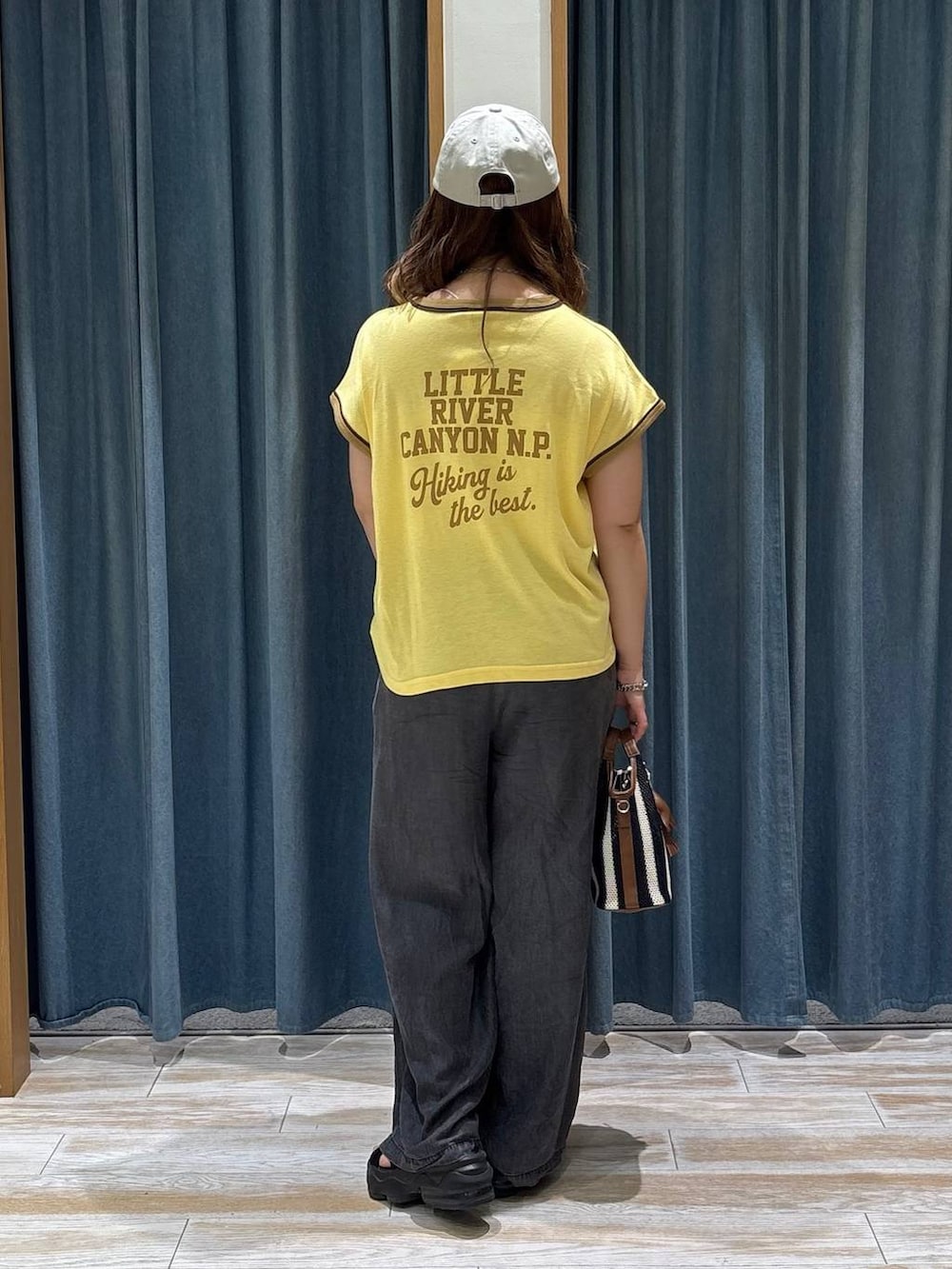 ブラック系のデニムパンツ、ブルー系のショルダーバッグ、イエロー系のTシャツ/カットソーを着用したレディースの夏コーディネートの3枚目の写真