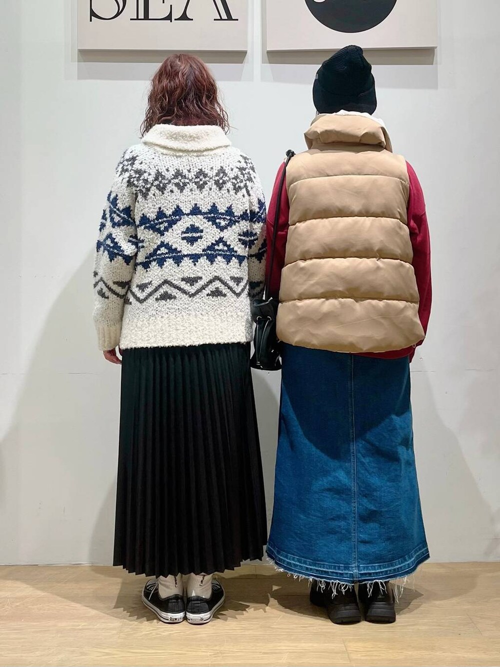 ブルー系のデニムスカート、レッド系のニット/セーター、ブラック系のショルダーバッグを着用したレディースの秋コーディネートの2枚目の写真