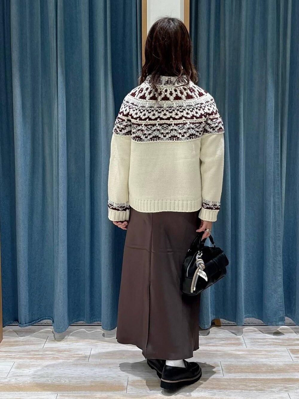 ブラック系のボストンバッグ、ブラック系のローファー、ホワイト系のニット/セーターを着用したレディースの秋コーディネートの3枚目の写真