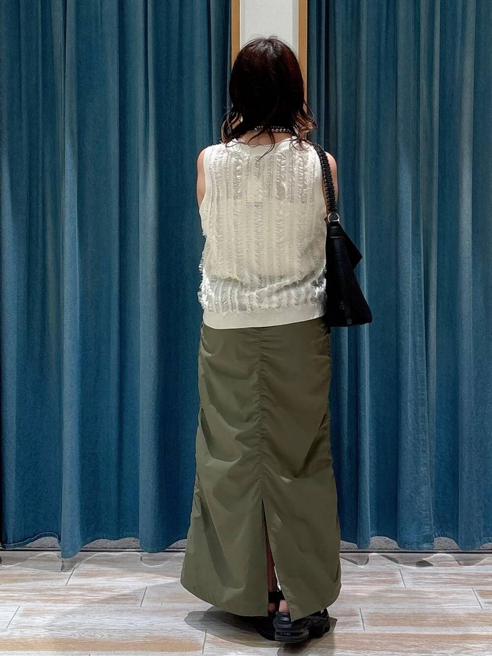 ホワイト系のキャミソール、ブラック系のハンドバッグ、グリーン系のスカートを着用したレディースの夏コーディネートの2枚目の写真