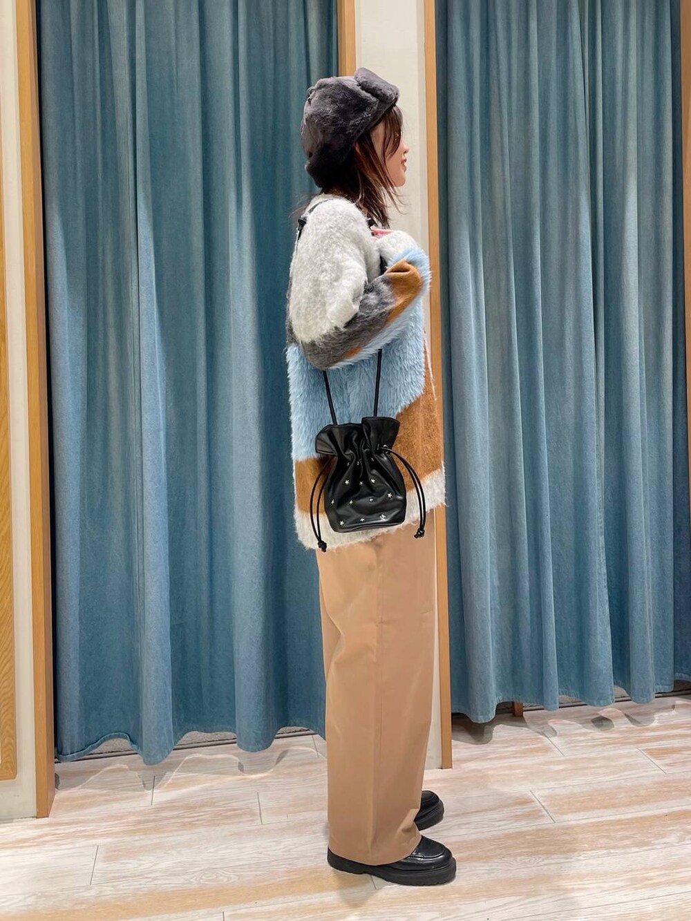 ブラック系のショルダーバッグ、ベージュ系のその他パンツ、グレー系のカーディガン/ボレロを着用したレディースの冬コーディネートの2枚目の写真