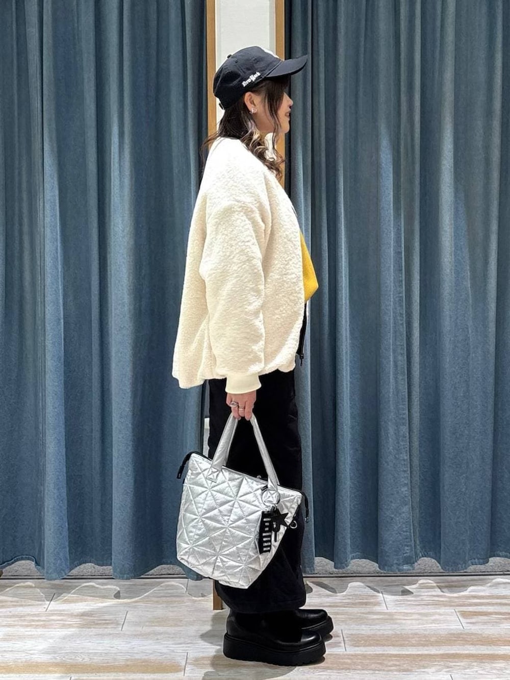 ブラック系のスカート、ブラック系のブーツ、イエロー系のニット/セーターを着用したレディースの冬コーディネートの2枚目の写真