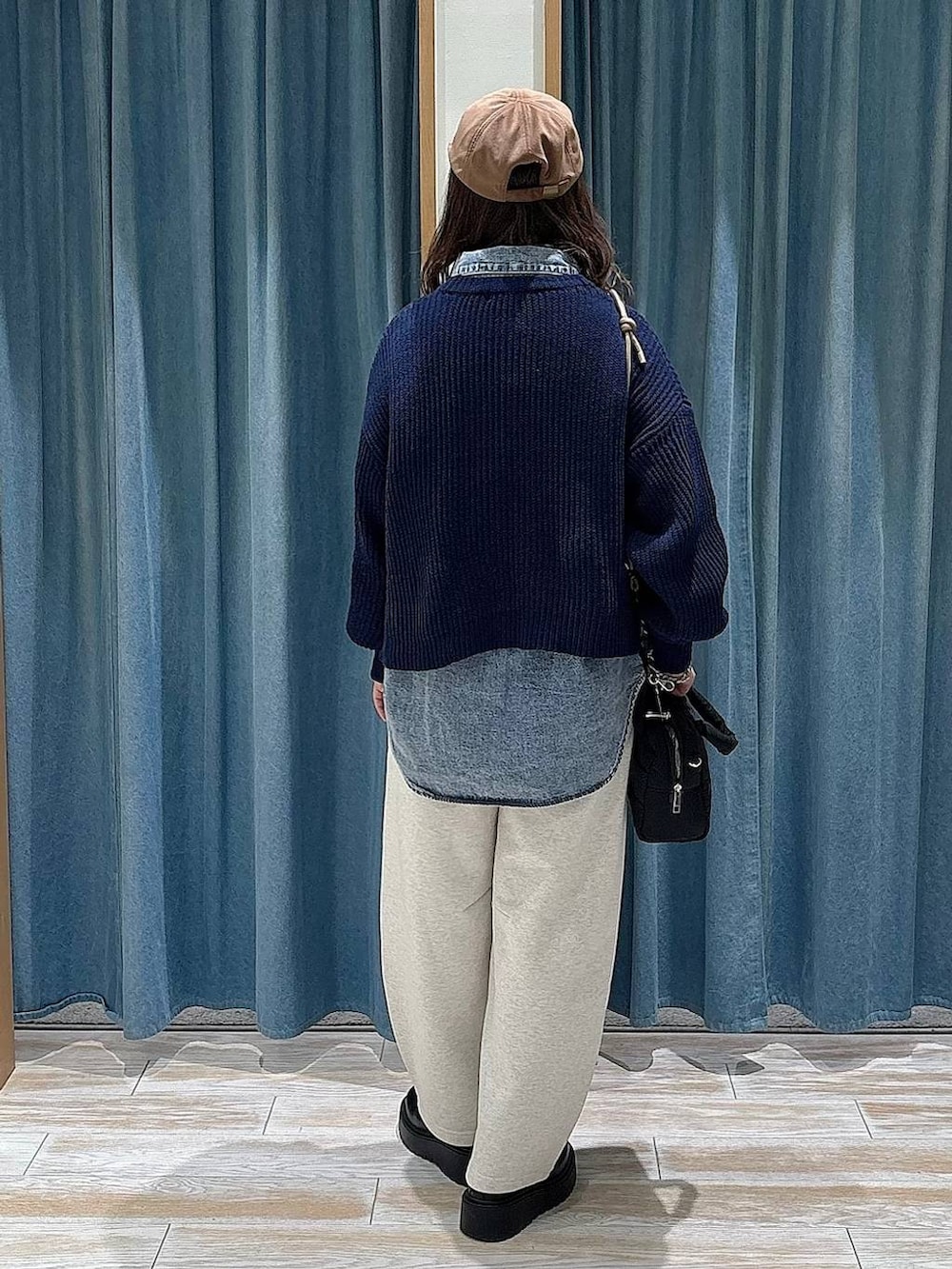 ブラック系のブーツ、ブラック系のボストンバッグ、ブルー系のニット/セーターを着用したレディースの冬コーディネートの3枚目の写真