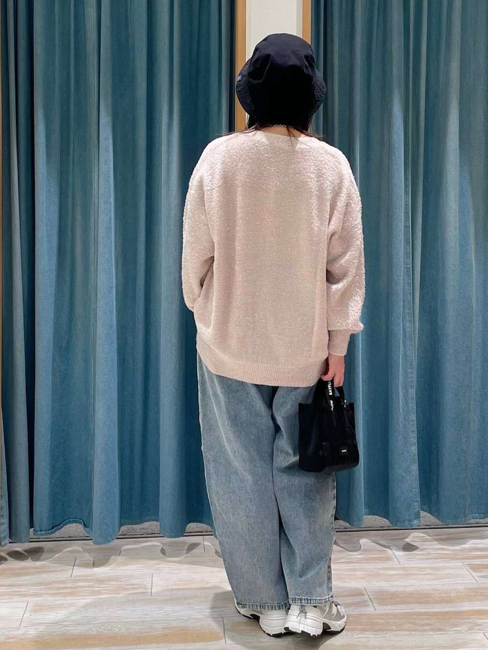 ブルー系のデニムパンツ、ブラック系のショルダーバッグ、ホワイト系のスニーカーを着用したレディースの冬コーディネートの3枚目の写真