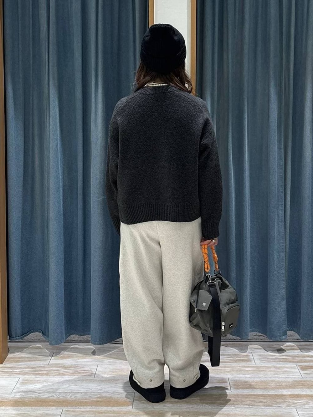 ブラック系のブーツ、グリーン系のハンドバッグ、グレー系のニット/セーターを着用したレディースの冬コーディネートの3枚目の写真