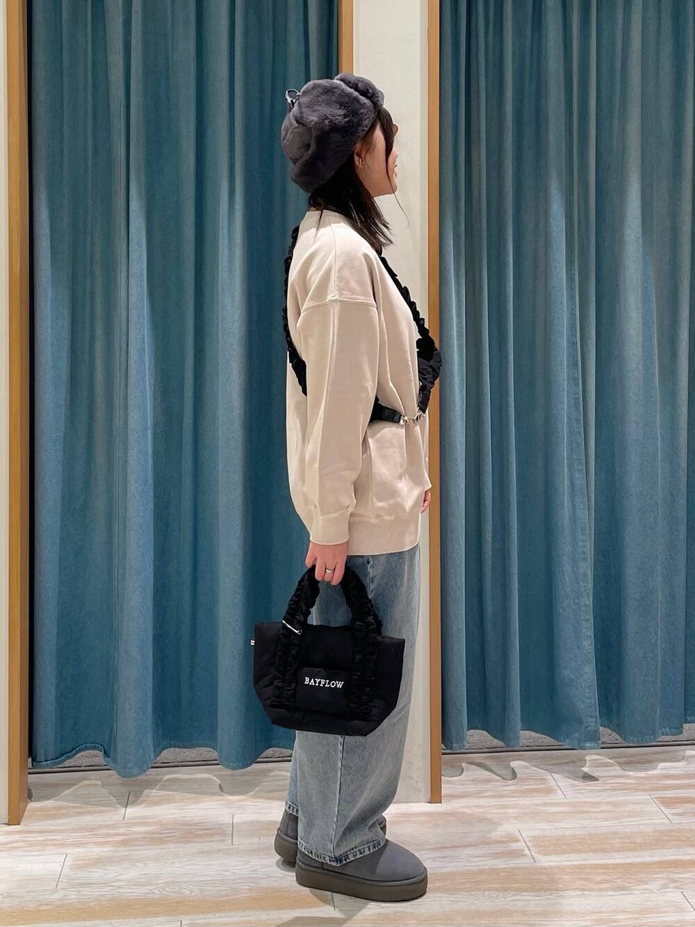 グレー系のブーツ、ブラック系のトートバッグ、ブルー系のデニムパンツを着用したレディースの冬コーディネートの2枚目の写真