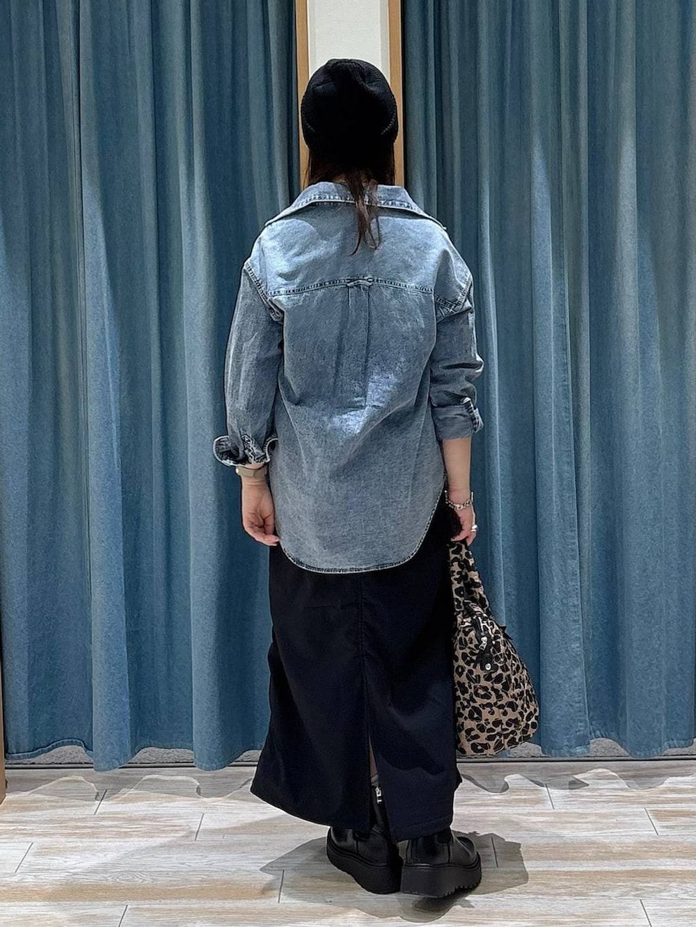 ブラック系のスカート、ブラック系のブーツ、ブルー系のシャツ/ブラウスを着用したレディースの冬コーディネートの3枚目の写真