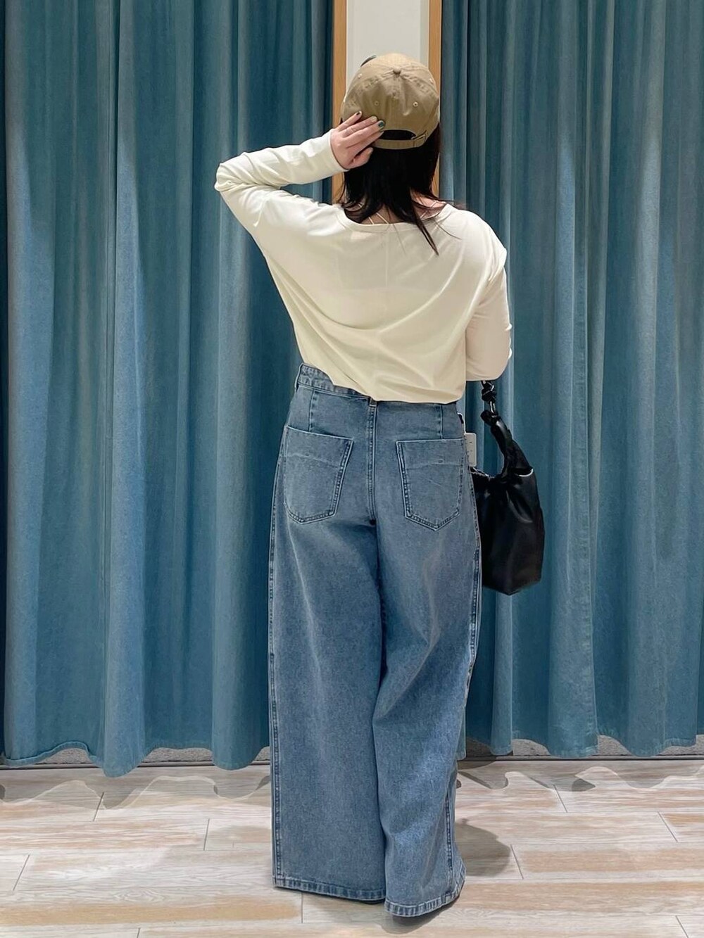 ブルー系のデニムパンツ、ホワイト系のTシャツ/カットソー、ブラック系のハンドバッグを着用したレディースの冬コーディネートの3枚目の写真