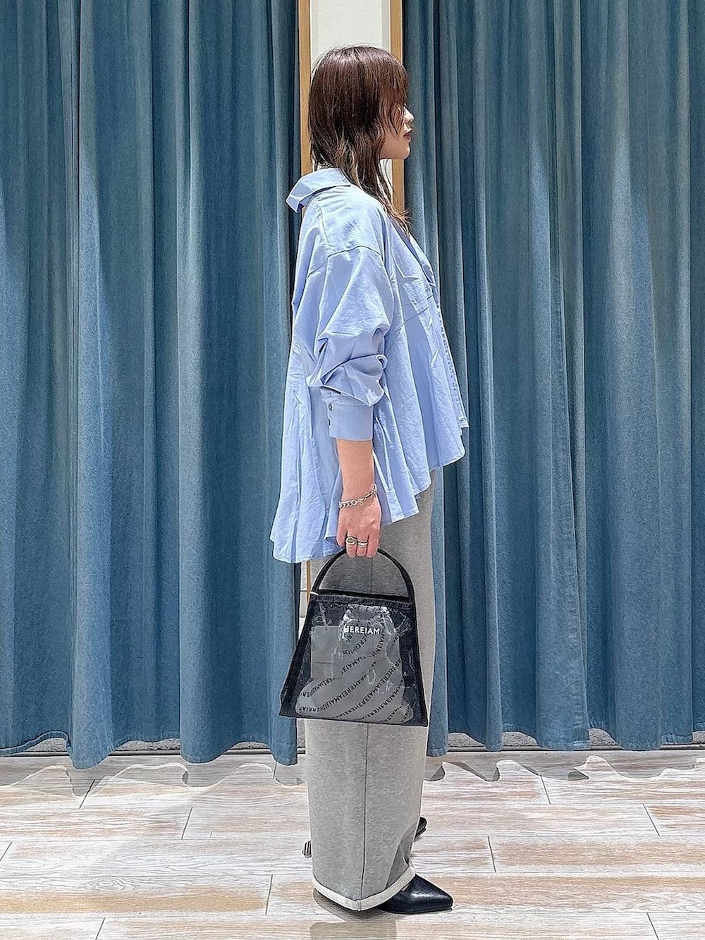 ブラック系のハンドバッグ、ブラック系のパンプス、ブルー系のシャツ/ブラウスを着用したレディースの春コーディネートの2枚目の写真