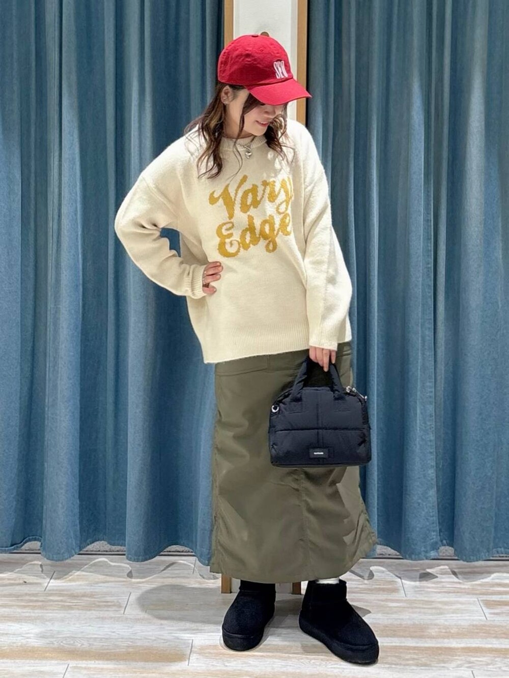 グリーン系のスカート、ブラック系のブーツ、ブラック系のボストンバッグを着用したレディースの秋コーディネートの4枚目の写真