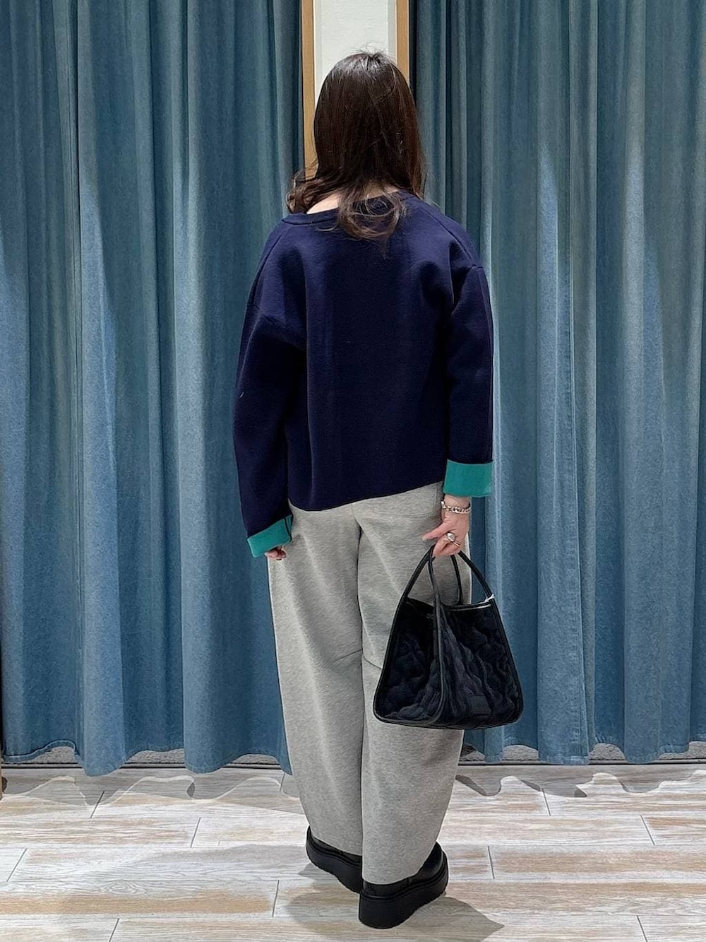 ブラック系のブーツ、ブラック系のハンドバッグ、ブルー系のカーディガン/ボレロを着用したレディースの冬コーディネートの3枚目の写真