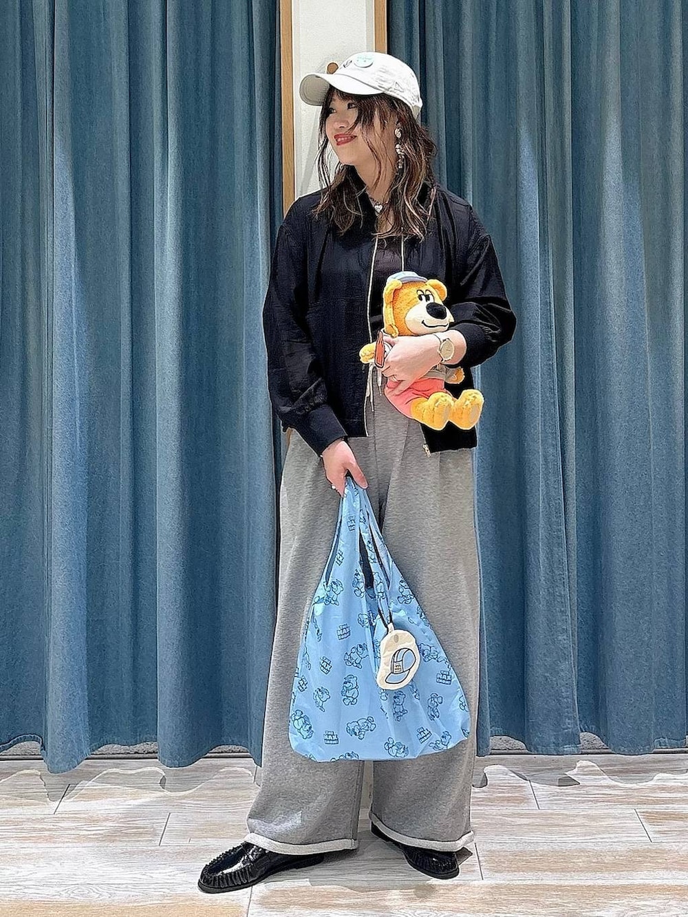 ブラック系のローファー、ブルー系のエコバッグ/サブバッグ、ブラック系のブルゾンを着用したレディースの春コーディネートの4枚目の写真