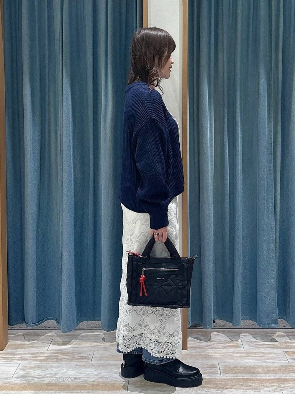 ブラック系のショルダーバッグ、ブラック系のブーツ、ブルー系のニット/セーターを着用したレディースの冬コーディネートの2枚目の写真