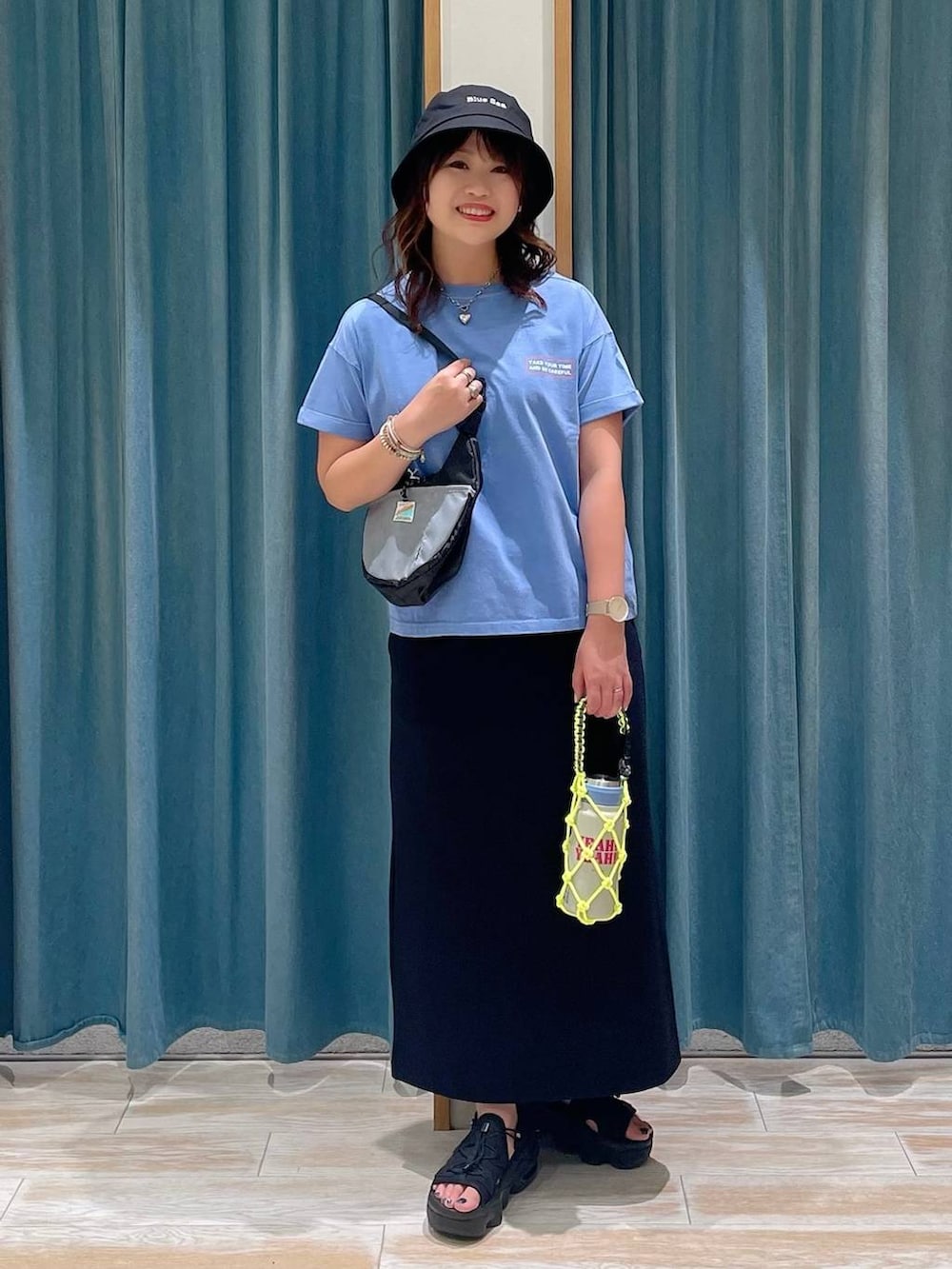 ブルー系のTシャツ/カットソー、ブラック系のショルダーバッグ、ブラック系のスカートを着用したレディースの夏コーディネートの4枚目の写真