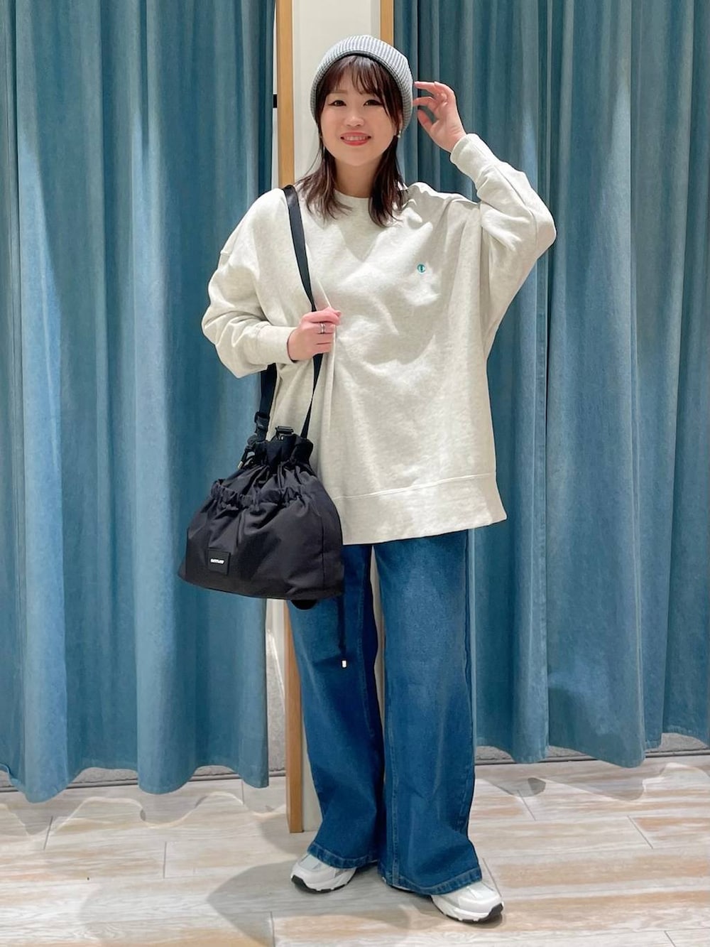 ブラック系のトートバッグ、ベージュ系のスウェット、ブルー系のデニムパンツを着用したレディースの冬コーディネートの2枚目の写真