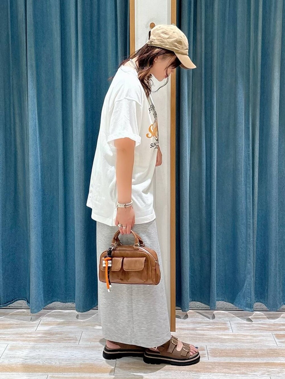 ベージュ系のサンダル、グレー系のスカート、ブラウン系のボストンバッグを着用したレディースの夏コーディネートの2枚目の写真