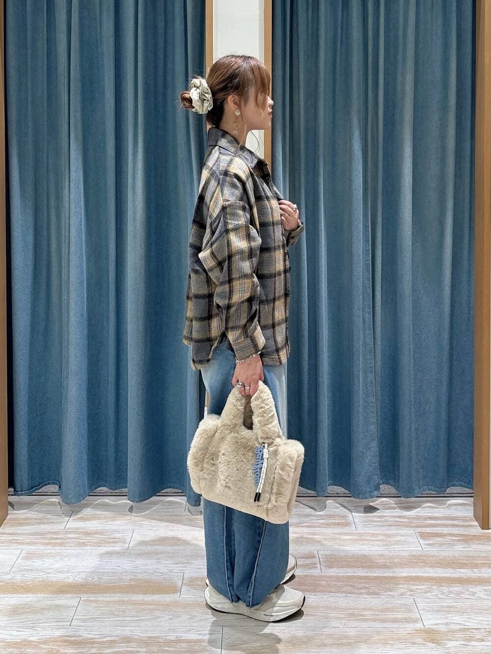 ブルー系のデニムパンツ、ベージュ系のトートバッグ、ホワイト系のスニーカーを着用したレディースの秋コーディネートの2枚目の写真