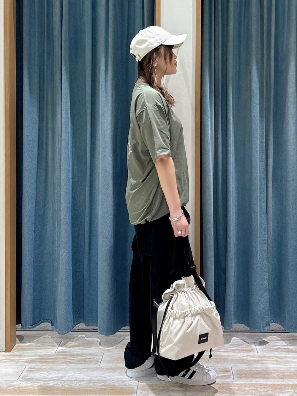 ホワイト系のトートバッグ、ホワイト系のスニーカー、ブラック系のカーゴパンツを着用したレディースの春コーディネートの2枚目の写真