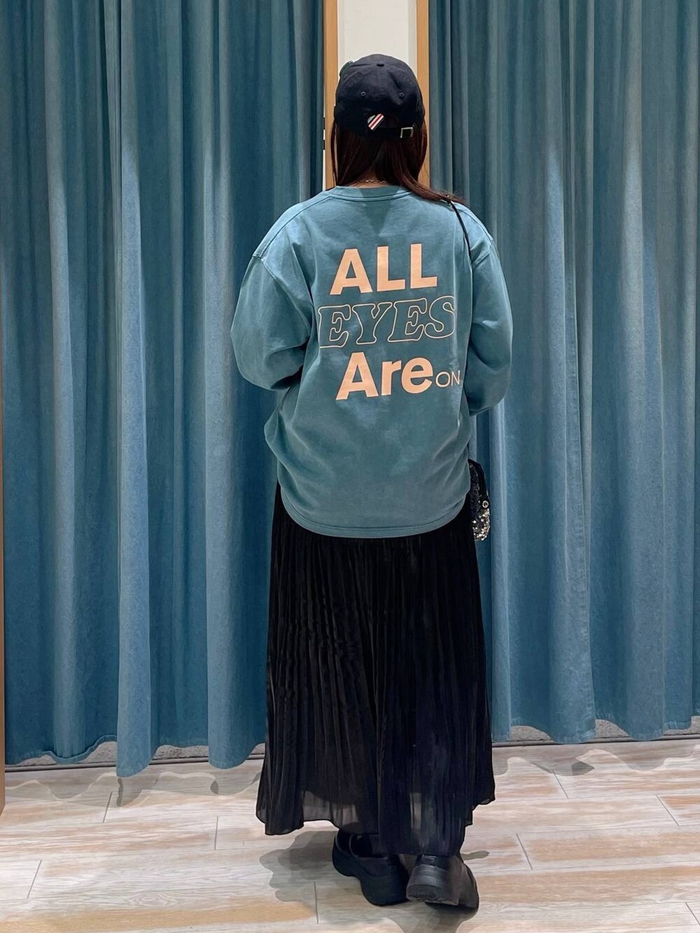 グレー系のショルダーバッグ、ブラック系のブーツ、ブラック系のスカートを着用したレディースの冬コーディネートの3枚目の写真