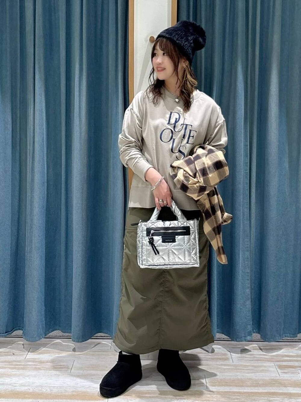 シルバー系のショルダーバッグ、グリーン系のスカート、ブラック系のブーツを着用したレディースの秋コーディネートの4枚目の写真