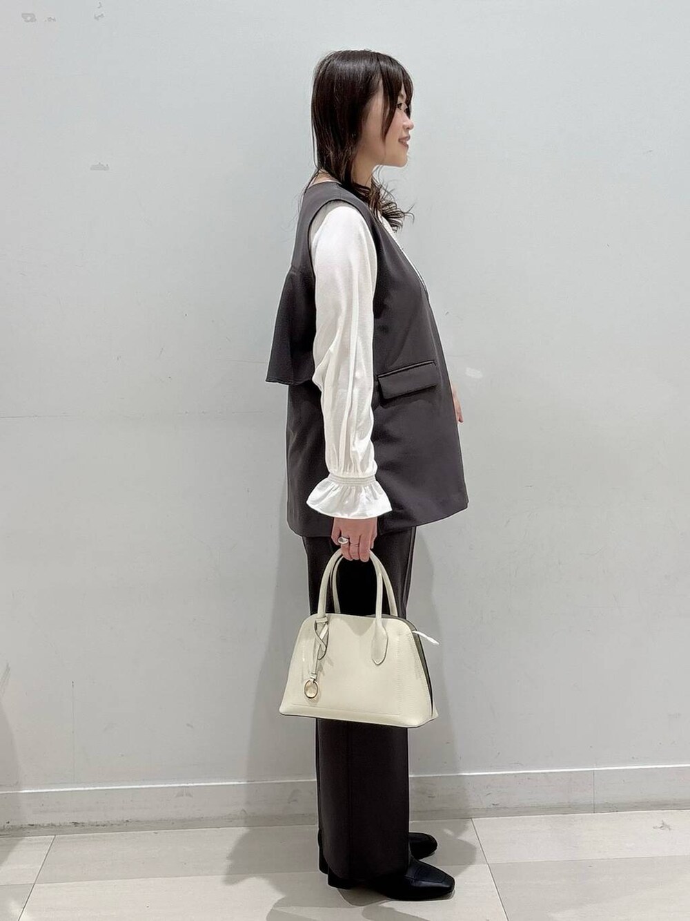 ブラック系のローファー、ホワイト系のショルダーバッグ、グレー系のセットアップを着用したレディースの冬コーディネートの2枚目の写真