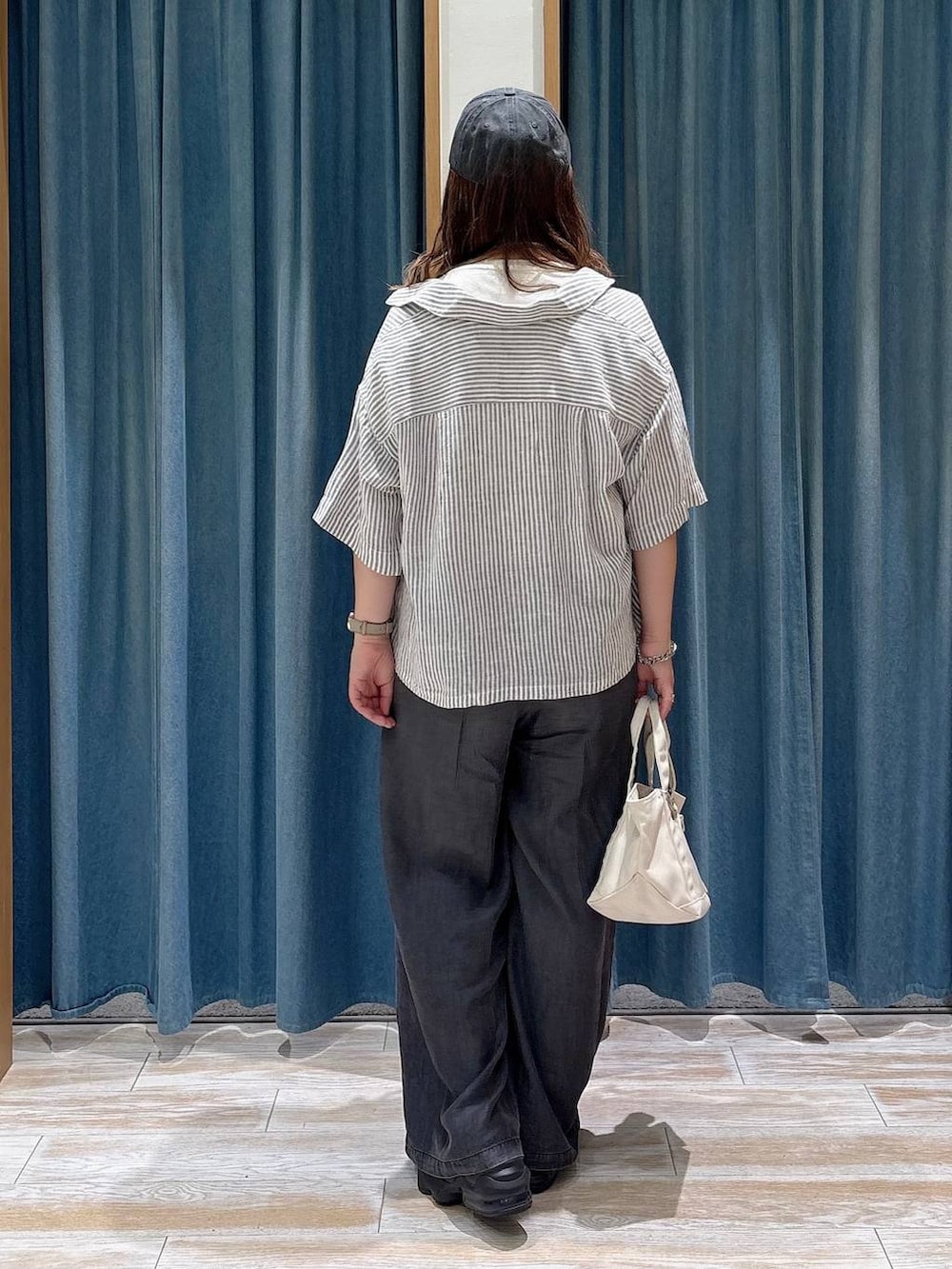 ブラック系のデニムパンツ、ホワイト系のトートバッグ、グレー系のシャツ/ブラウスを着用したレディースの夏コーディネートの3枚目の写真