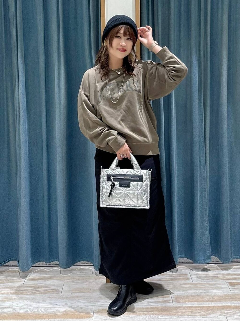 シルバー系のショルダーバッグ、ブラック系のスカート、ブラック系のブーツを着用したレディースの秋コーディネートの4枚目の写真